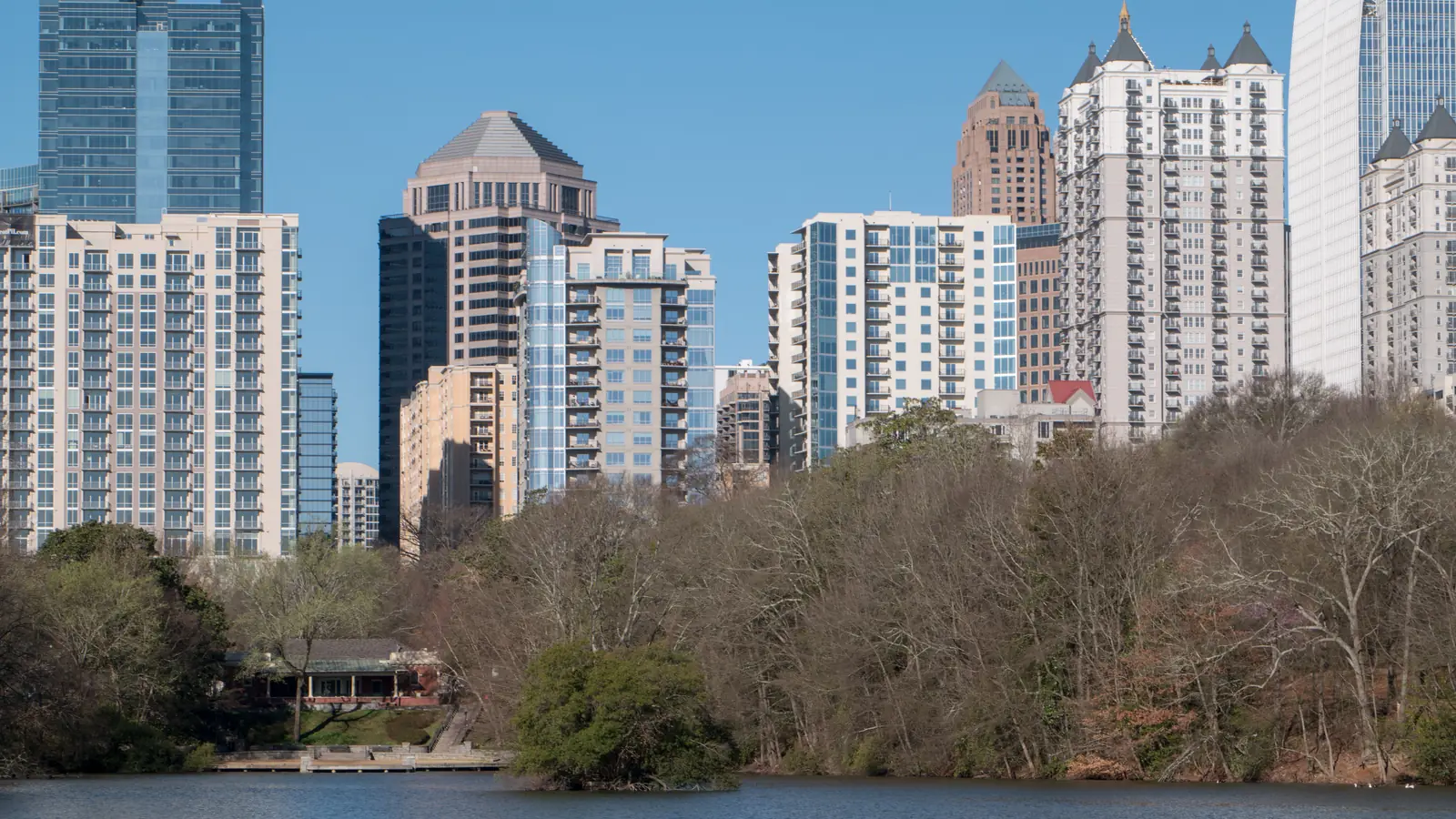 Midtown Atlanta's towers under a clear blue sky, seen across Lake Clara Meer in Piedmont Park.