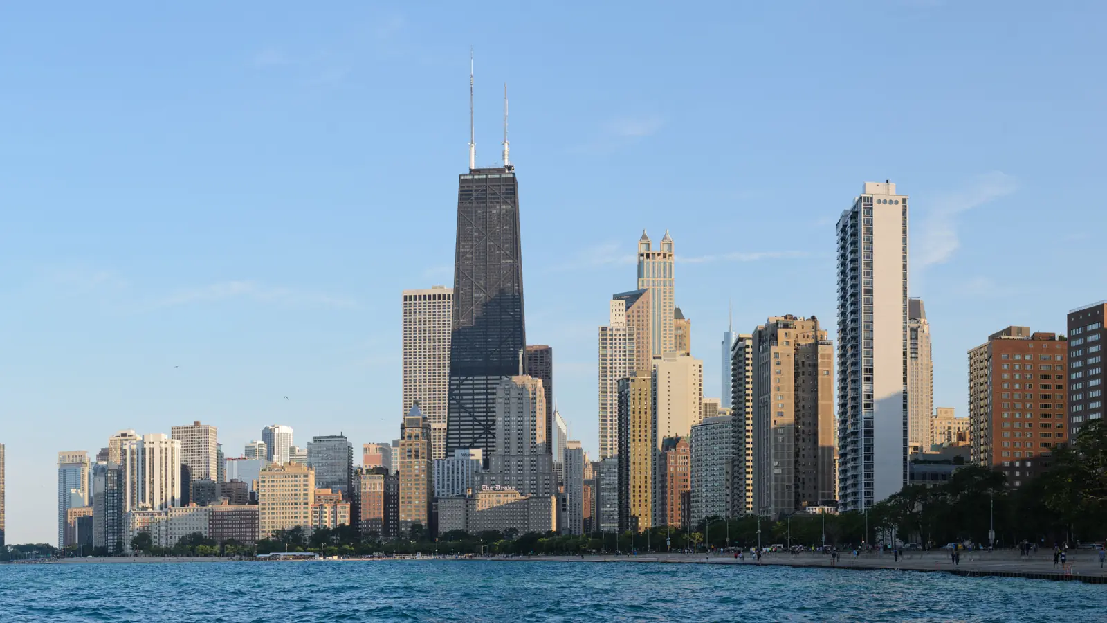 Chicago's lakefront towers and the John Hancock Center in late-afternoon sun, seen from North Avenue Beach across Lake Michigan.