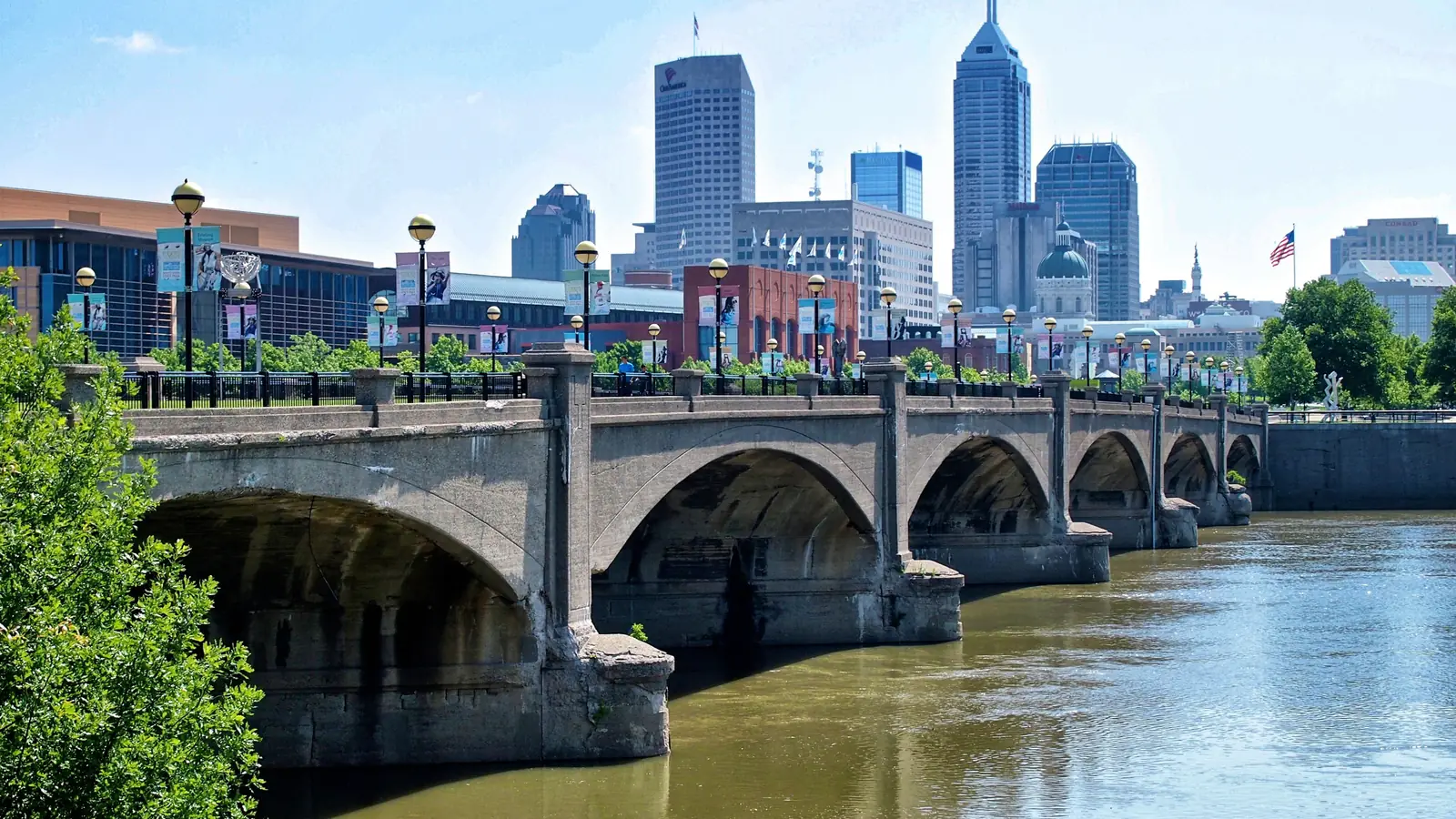 Downtown Indianapolis towers behind a stone bridge over the White River.
