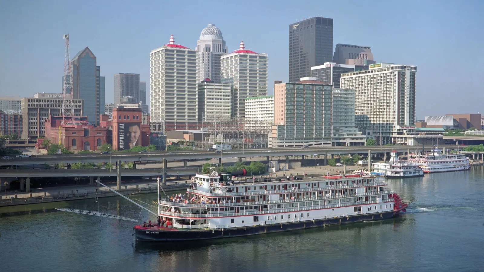 Downtown Louisville above the Ohio River with the Delta Queen steamboat at the waterfront.