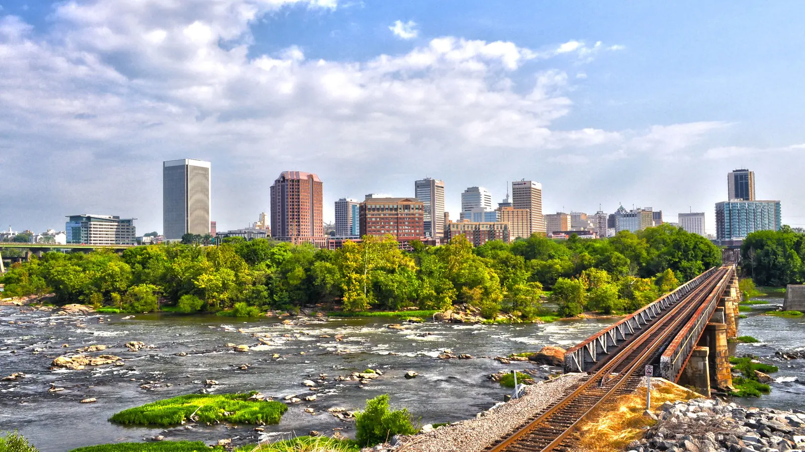 Downtown Richmond, Virginia, across the rocky James River with a railroad trestle in the foreground.