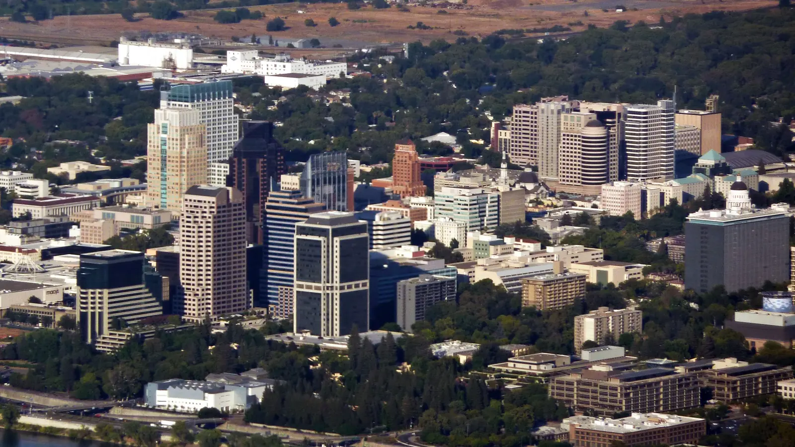 Downtown Sacramento seen from the air, office towers among tree-lined streets.