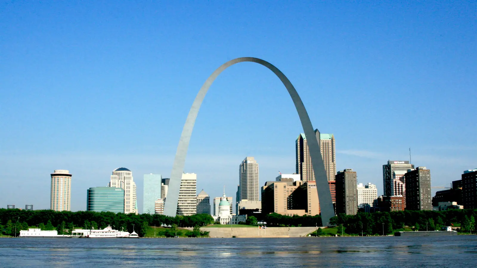 The Gateway Arch and downtown St. Louis across the Mississippi River under a clear sky.