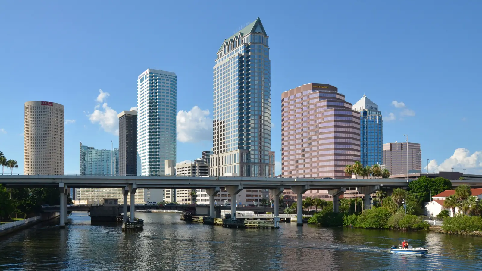 Downtown Tampa towers above the Hillsborough River under a blue sky.