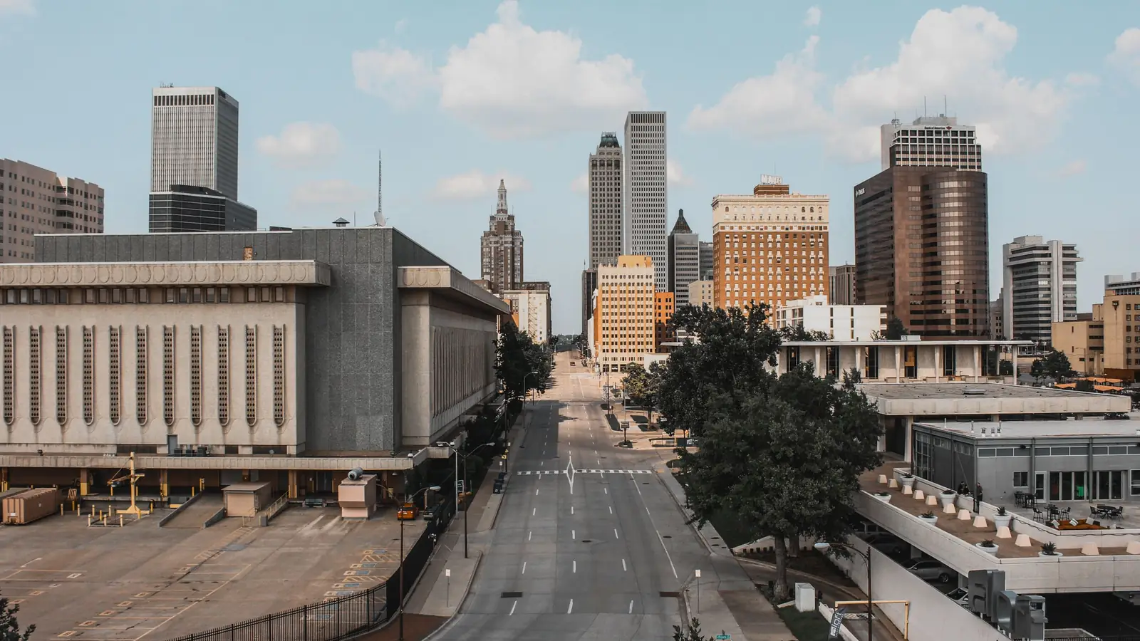 Downtown Tulsa office towers lining a wide street under a light blue sky.